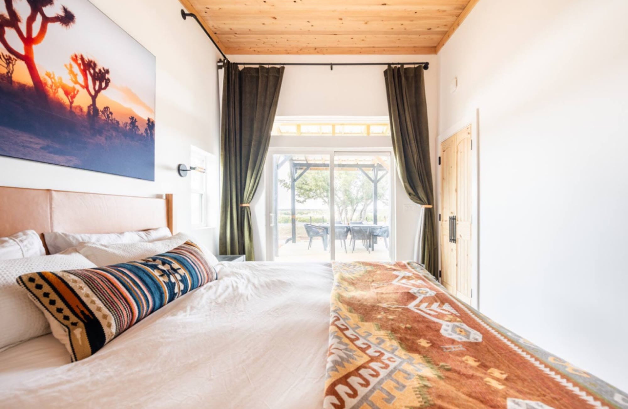 Bedroom with a patterned blanket, cedar ceiling and glass doors to the porch