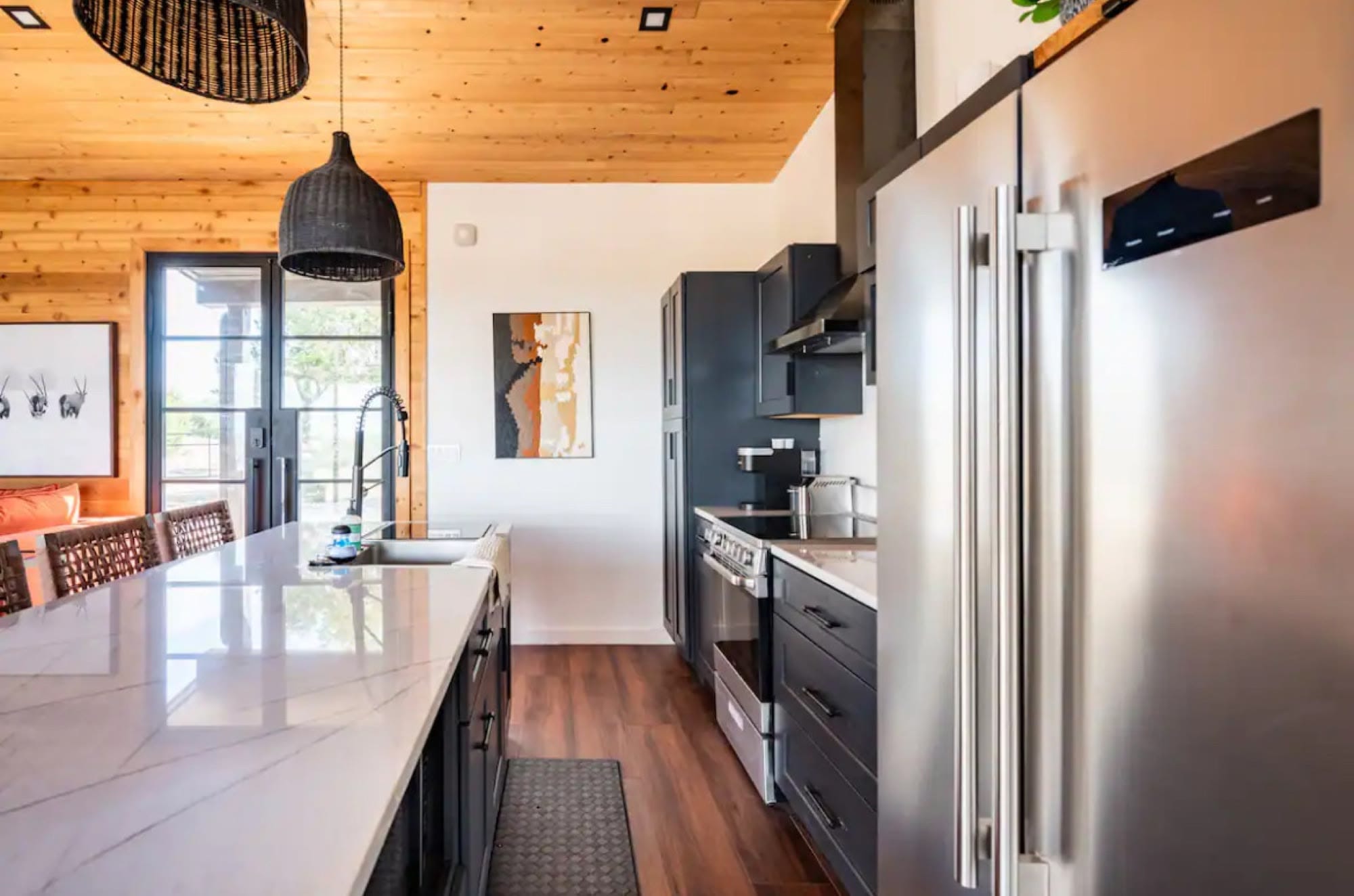 Kitchen with a white stone island, black cabinets and a stainless refrigerator