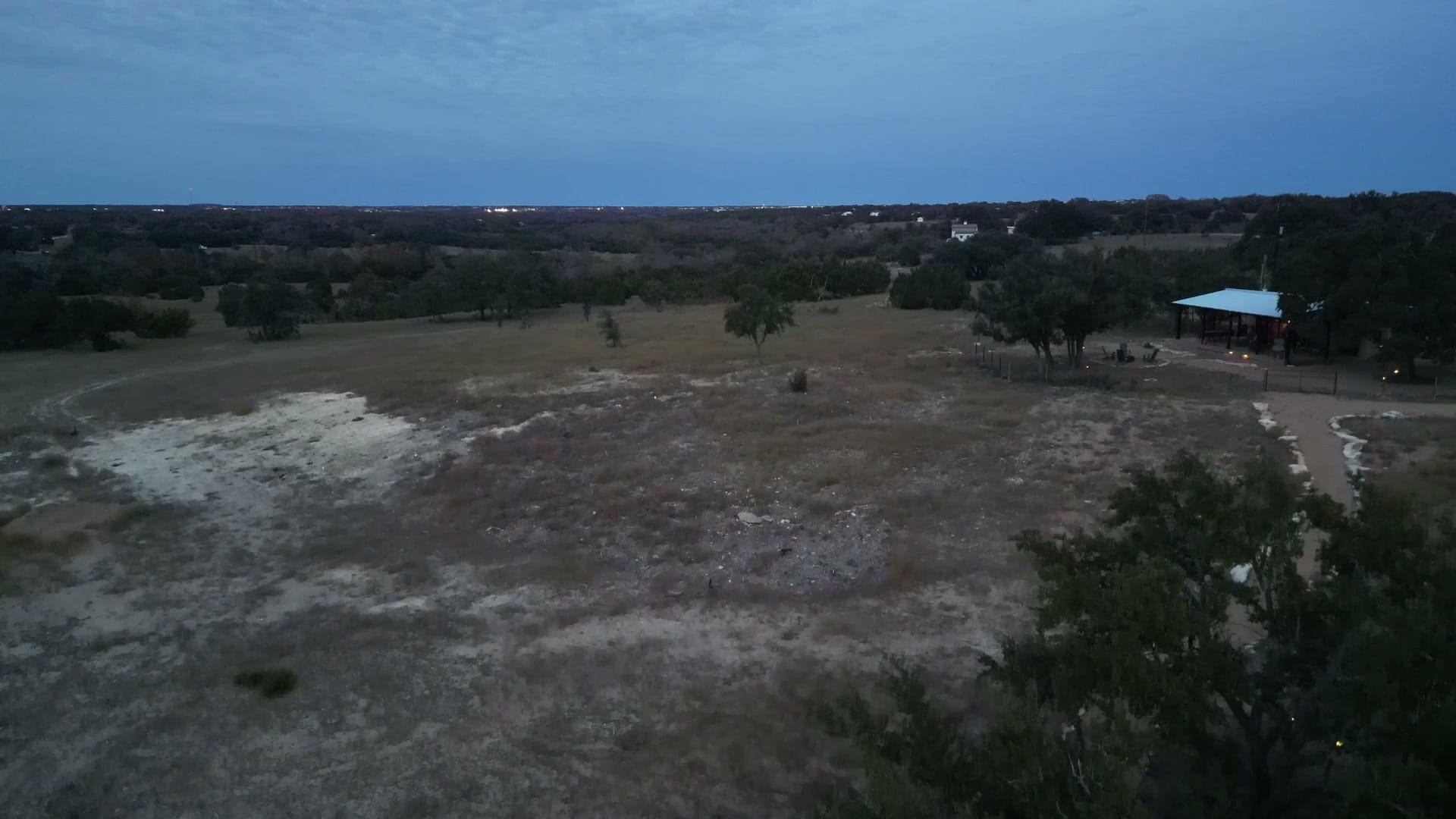 Drone view of the cabin and surrounding pasture at dusk